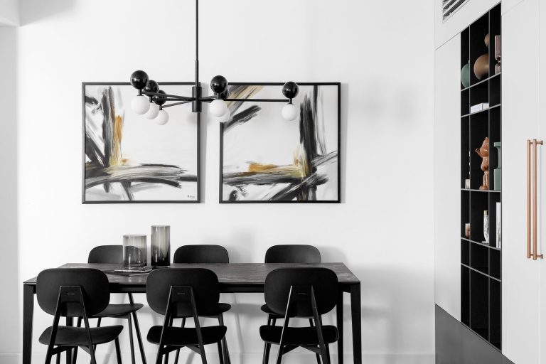 פינת אוכל מונוכרומטית בגני תקווה עם שולחן כהה, כסאות שחורים וספרייה שחורה