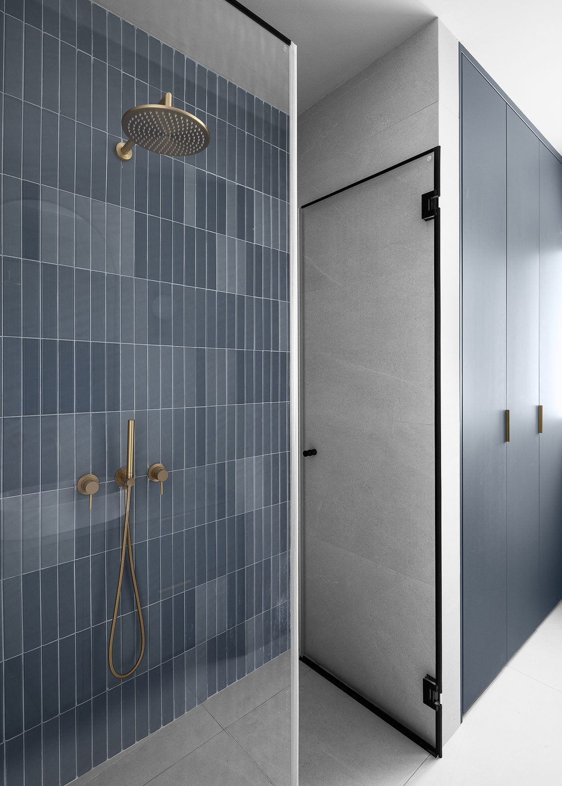 מקלחון עם חיפוי קרמיקה כחולה וברזים בגימור פליז